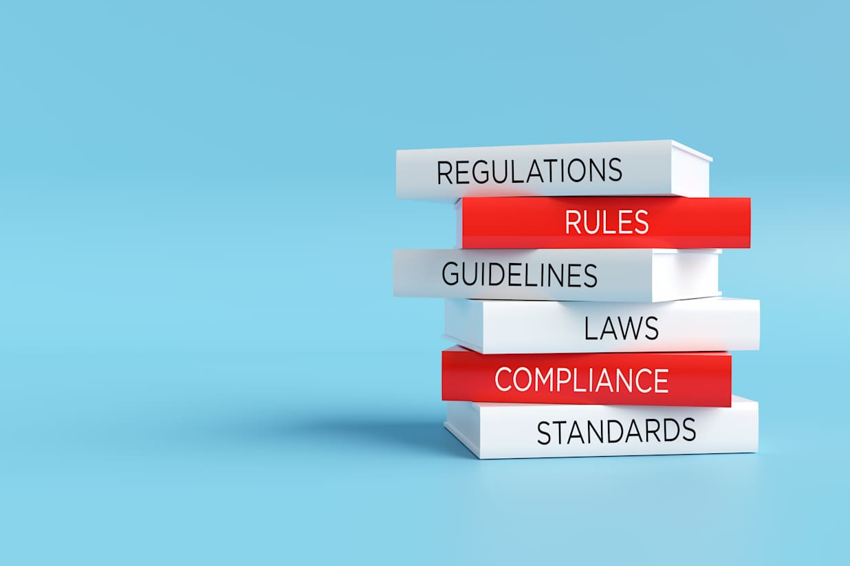 Books forming a stack with words regulations, rules, guidelines, laws, compliance and standards, compliance concept.